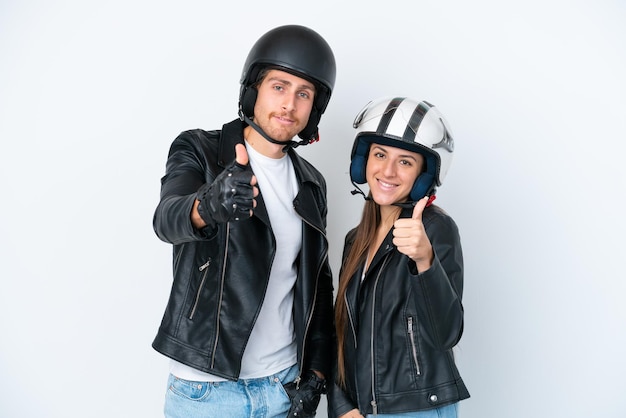 Jong Kaukasisch paar met een motorhelm geïsoleerd op een witte achtergrond die een duim omhoog gebaar geeft omdat er iets goeds is gebeurd