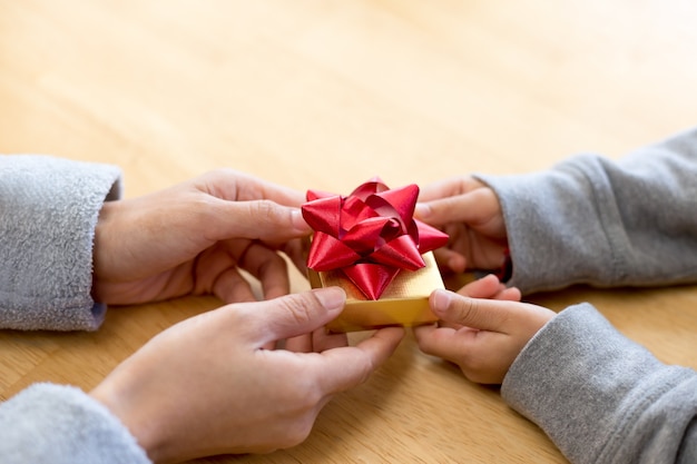 Foto jong kind een geschenk doos overhandigen aan moeder