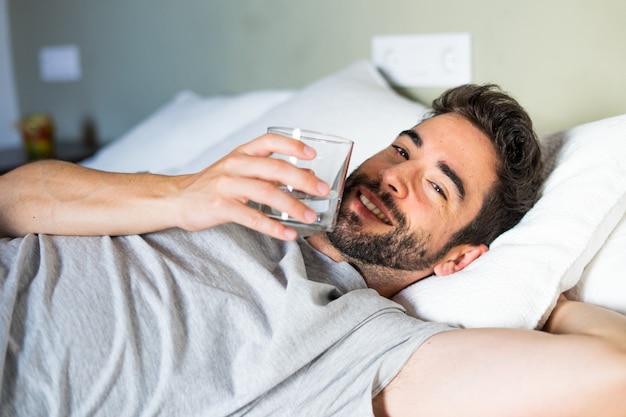 Jong knap mensen drinkwater in slaapkamer