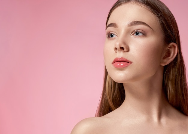 Jong, knap model met natuurlijke make-up poseren op roze