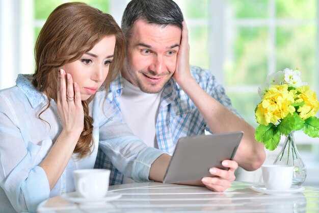 Jong koppel aan tafel zitten en kijken naar digitale tablet