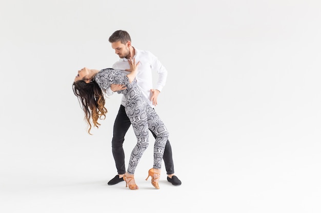 Jong koppel dansen latin dans bachata, merengue, salsa, kizomba. Twee elegantie poseren op witte achtergrond met kopie ruimte