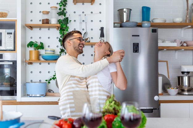 Jong koppel dansen samen in hun keuken gelukkige man en vrouw dansen in de keuken verliefde paar samen genieten