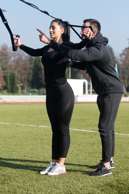 Jong koppel doen Crossfit met Trx Fitness bandjes in stadspark gebied opleiding en oefenen voor uithoudingsvermogen gezonde levensstijl Concept buiten