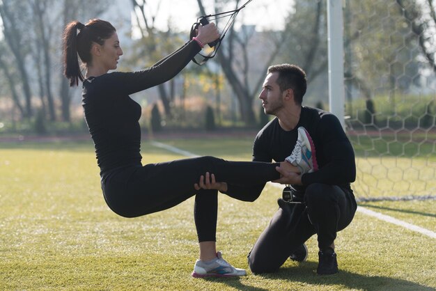 Jong koppel doen Crossfit met Trx Fitness bandjes in stadspark gebied opleiding en oefenen voor uithoudingsvermogen gezonde levensstijl Concept buiten