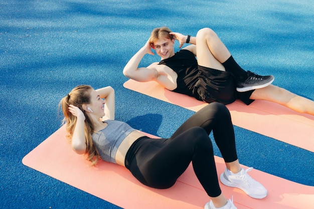 Jong koppel doet sportoefeningen op een yogamat in het stadion