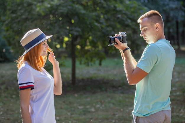 Jong koppel fotograferen van elkaar buitenshuis in zomer park.