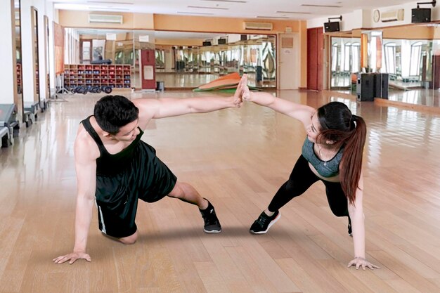 Jong koppel geeft high five in het fitnesscentrum.