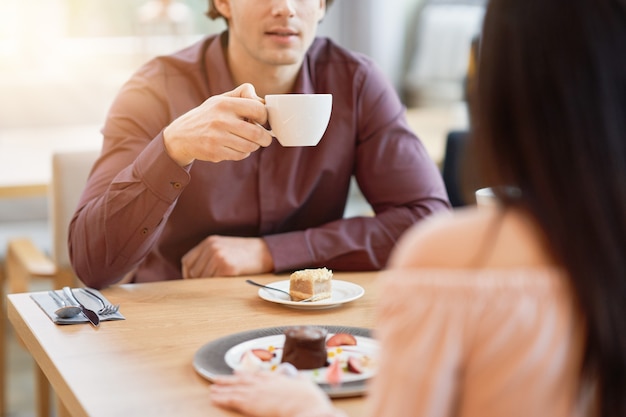 jong koppel genieten van koffie en cake in café