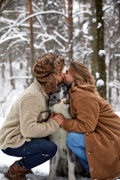 Jong koppel glimlachend en plezier in het winterpark met hun husky hond