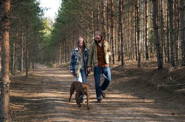 Jong koppel hand in hand en wandelen samen met hun hond in het park