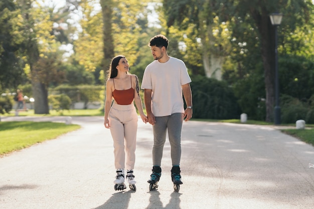 Jong koppel hand in hand tijdens het schaatsen in een pad van een park