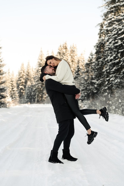 Jong koppel in de sneeuw in de winter in het park liefde en vakantie concept gelukkig paar knuffelen en lachen buiten in de winter