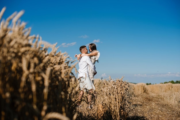 Jong koppel in het tarweveld op zonnige zomerdag. verliefde paar veel plezier in gouden veld. romantisch paar in casual kleding outdoodrs op grenzeloos veld