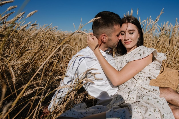 Jong koppel in het tarweveld op zonnige zomerdag. Verliefde paar veel plezier in gouden veld. Romantisch paar in casual kleding outdoodrs op grenzeloos veld