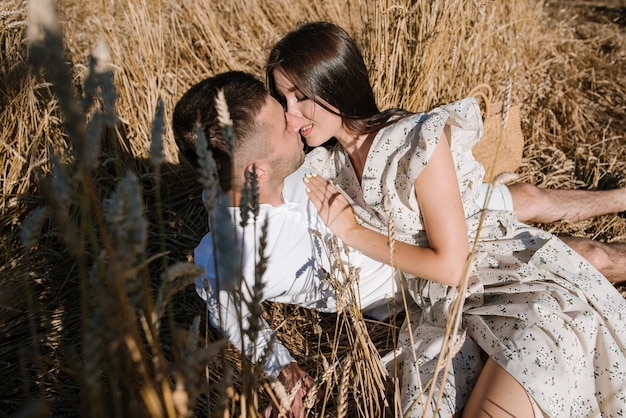 Jong koppel in het tarweveld op zonnige zomerdag. verliefde paar veel plezier in gouden veld. romantisch paar in casual kleding outdoodrs op grenzeloos veld