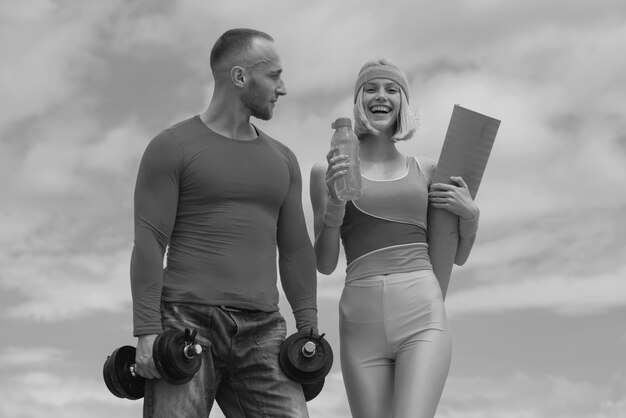 Jong koppel in liefde training buiten gespierde sporttrainer met vrolijke lachende jonge vrouw holdin