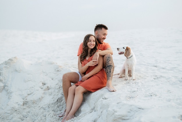 Jong koppel in oranje kleren met hond in het witte woestijnzand