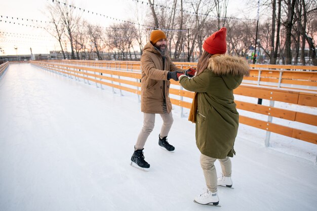 Jong koppel in warme kleding met plezier op de ijsbaan buiten tijdens de wintervakantie