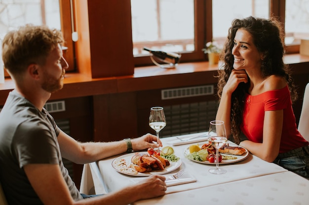 Jong koppel lunchen met witte wijn in het restaurant