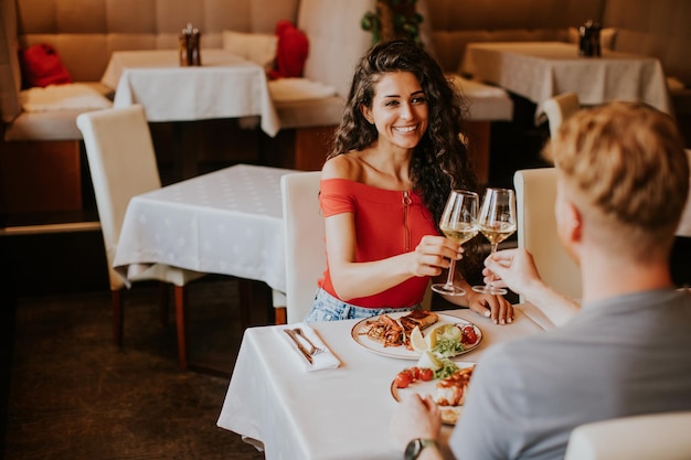 Jong koppel lunchen met witte wijn in het restaurant