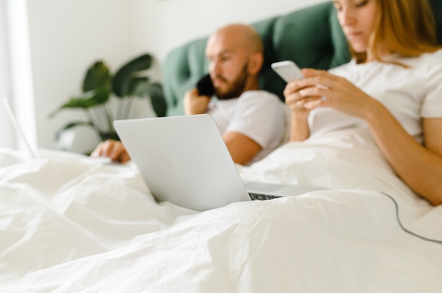 Jong koppel maakt gebruik van laptop in bed. freelancer ochtend.