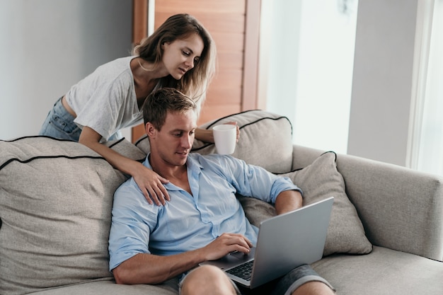 Jong koppel met behulp van laptop samen zittend op de Bank