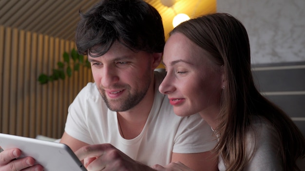 Jong koppel met behulp van tablet op bed in de slaapkamer 's avonds laat.