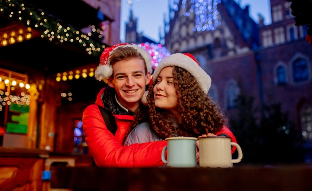 Jong koppel met drankjes op kerstmarkt in Wroclaw, Polen