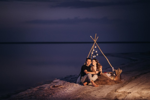 Jong koppel met een picknick op het strand van een roze meer