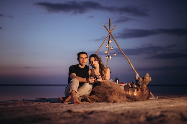 Jong koppel met een picknick op het strand van een roze meer