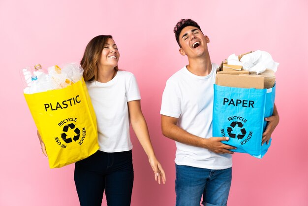 Jong koppel met een zak vol plastic en papier op roze lachen