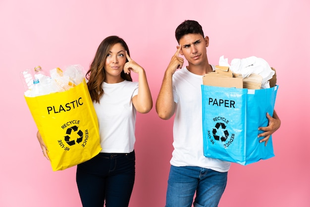 Jong koppel met een zak vol plastic en papier op roze twijfels en denken