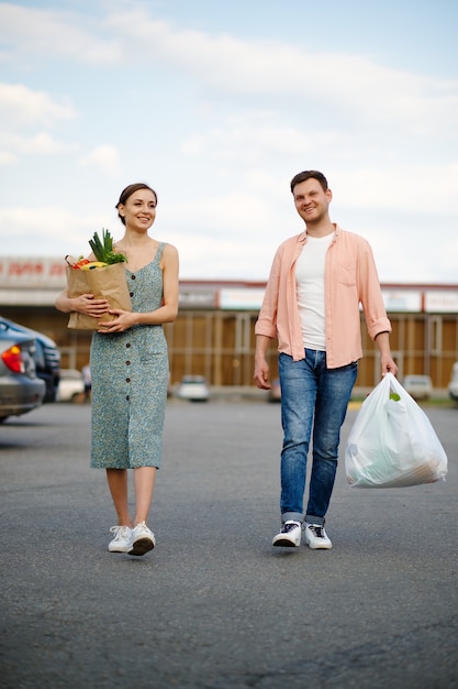 Jong koppel met tassen op supermarkt parking