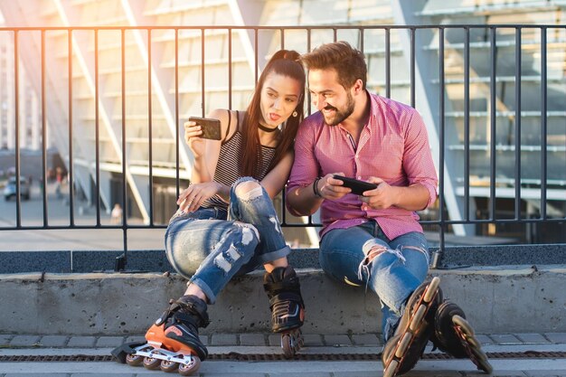 Jong koppel met telefoons meisje dat tong laat zien, neemt een grappige selfie