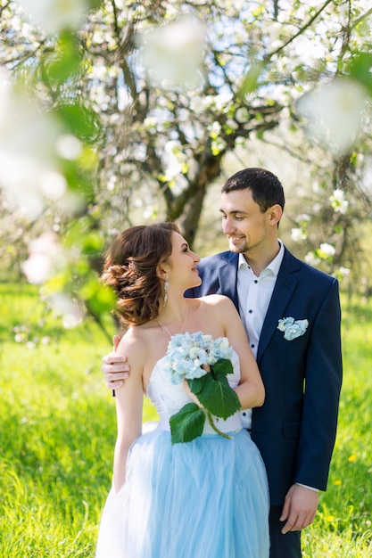 Jong koppel omarmen in bloeiende lentetuin. Liefde en romantisch thema.