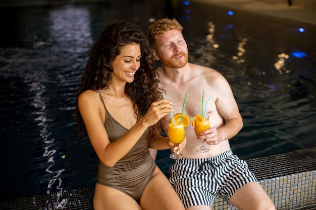 Jong koppel ontspannen en vers sinaasappelsap drinken aan het zwembad?