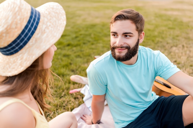 Jong koppel op de picknick in het park praten en ontspannen