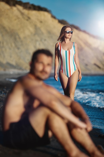 Jong koppel op het strand. Focus op de vrouw die naar de zee op de achtergrond kijkt.