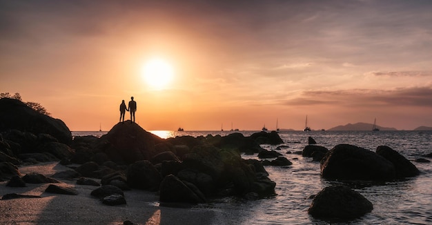 Jong koppel op zoek naar de zonsondergang aan de kust in de tropische zee