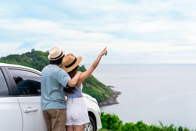 Jong koppel reiziger kijken naar het prachtige uitzicht op zee met hun auto tijdens het rijden road trip op vakantie reizen