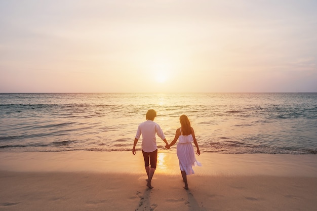 Jong koppel reiziger op zoek naar prachtige zonsondergang op het strand