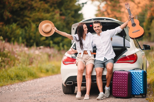 Jong koppel reizigers zitten in de kofferbak van een auto op zomervakantie auto