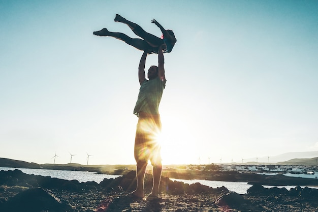 Jong koppel silhouet doen acroyoga buiten op het strand - vrouw en man training op avondtijd bij zonsondergang - soft focus op lichamen - gezonde levensstijl concept