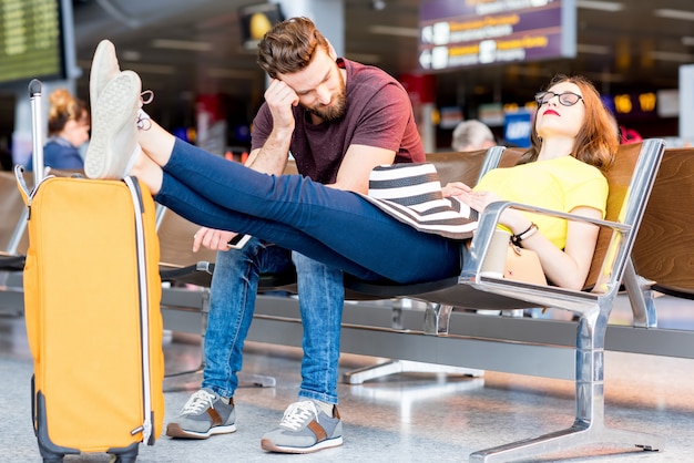 Jong koppel slapen op de stoelen in de wachtkamer van de luchthaven. Lang wachten op het vliegtuig