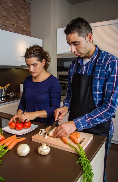 Jong koppel snijden groenten in de keuken om voedsel te bereiden