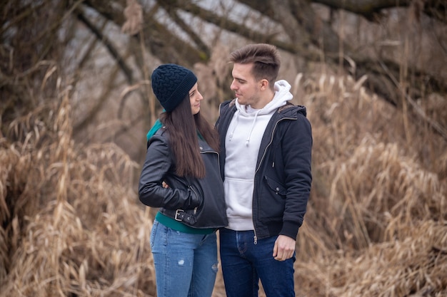 Foto jong koppel staande in de natuur op een winterdag, kijkend naar elkaar