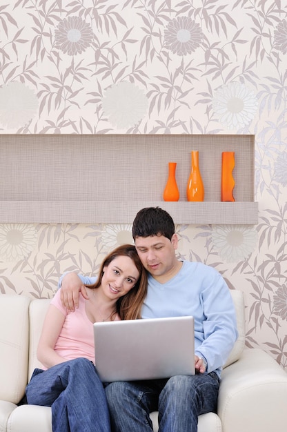 jong koppel thuis met moderne woonkamer binnen bezig met laptop op huisfinanciën en schaven