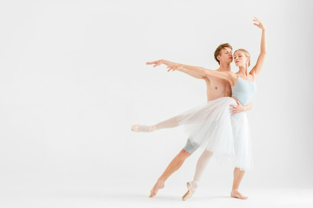 Jong koppel van moderne balletdansers poseren op witte studio achtergrond