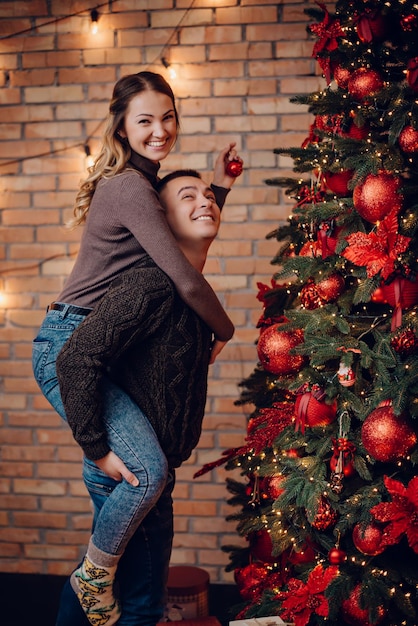 Foto jong koppel verkleden kerstboom thuis